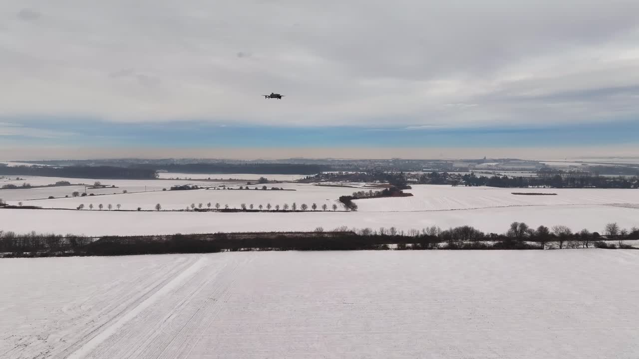 Drone hovering over vast snow covered agricultural fields and farmland, Czechia