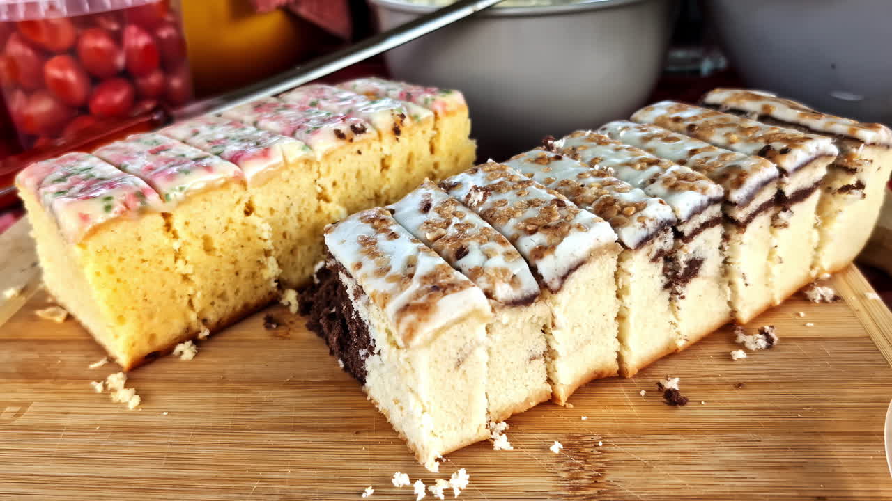 Sliced iced sponge cakes on wooden tray at buffet