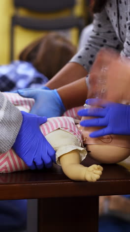 training for first aid. practitioners doing cardiopulmonary resuscitation on baby dummies. training practice of a chest compression and breathing. education of medicine. vertical video