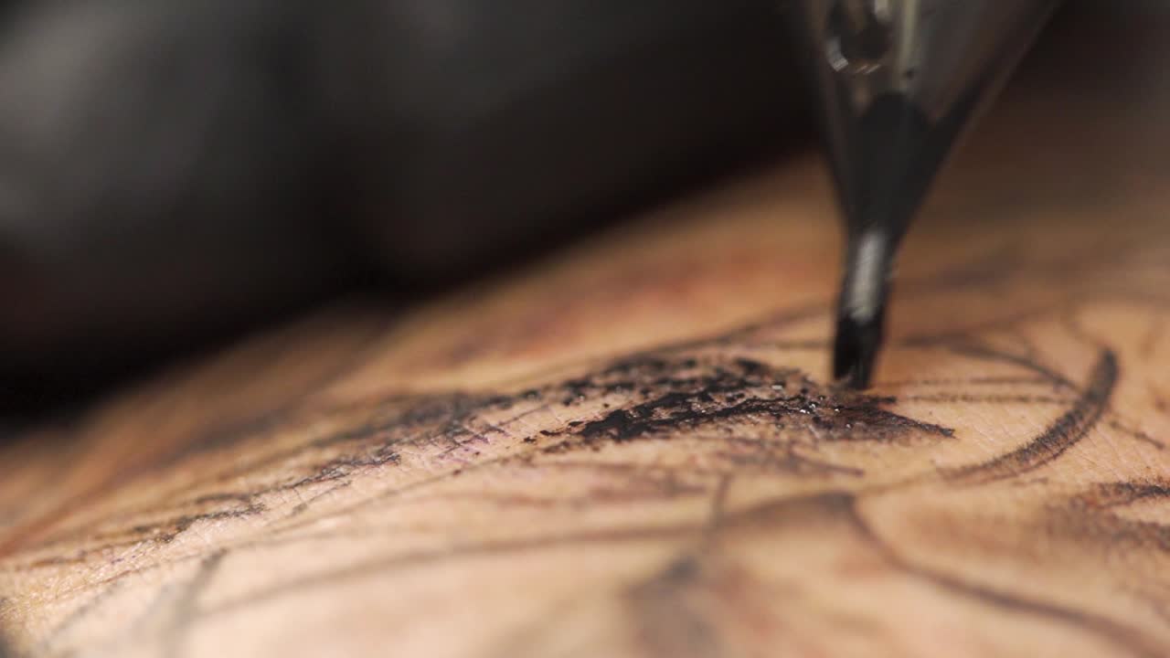 Macro shot of tattooing process wipping in a professional tattoo studio. Shot in slow motion 120fps