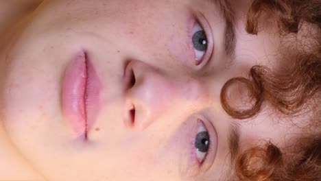 closeup of the face of a curly redhaired boy a student on a light brown background closeup of the face of a curly redhaired boy a student on a light brown background the emotion of peace happiness relaxation meditation a guy with narrowed eyes