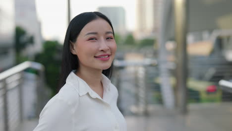 young asian woman smiling on an urban pedestrian bridge