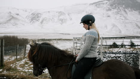woman horseback riding in snowy icelandic landscape