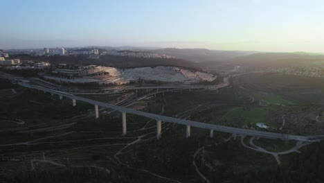 pull-back-shot-of-sunset-over-a-forest-and-a-train-passing-over-a-bridge