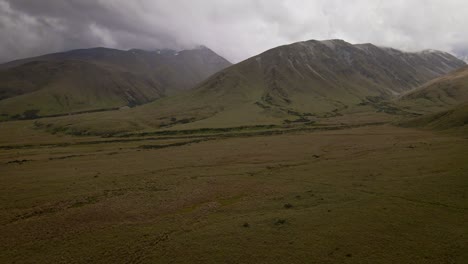 amplias llanuras de matas al pie de una escarpada cadena montañosa que toca pesadas nubes de tormenta arriba