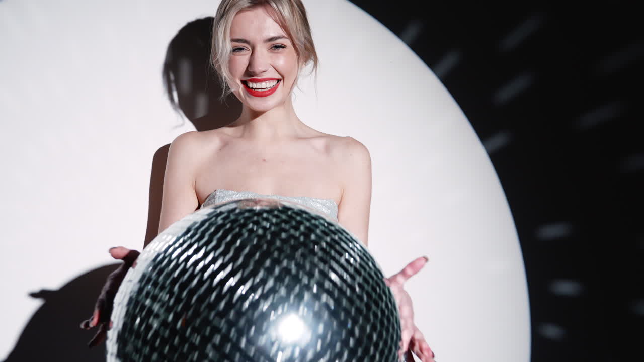 Donna in abito argentato con palla da discoteca
