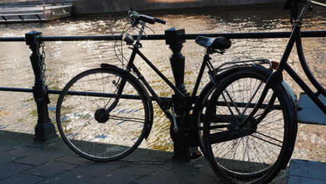 bicycle by canal railings in amsterdam