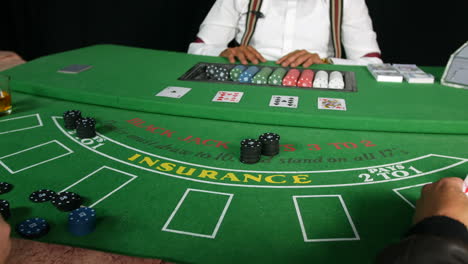 poker players placing bets with poker chips on a black jack tabble in a casino