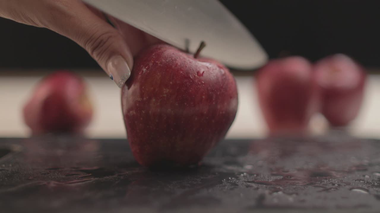 4K Fresh apple on a table with warm light and black background in an indoor dark mood with simple props arranged beside each other