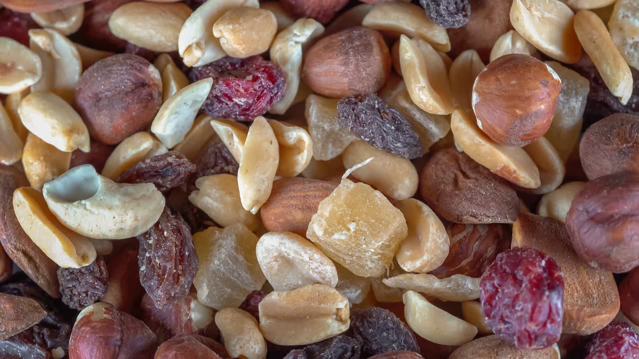 Many mixed nuts and dried fruits at rotating background - looping video