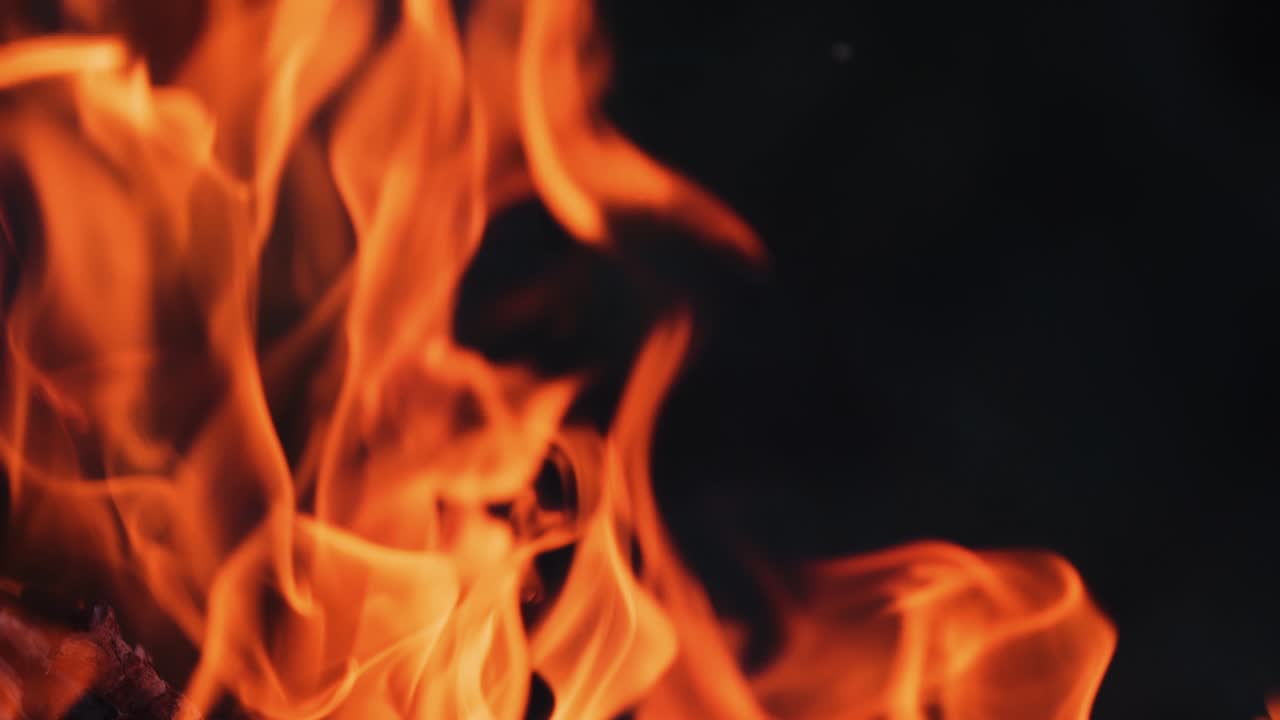 Fuoco vivido su sfondo nero. Fiamma rossa e gialla di un falò che brucia intensamente di notte. Primo piano.