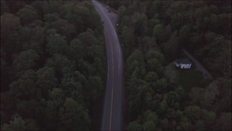 Coche-Conduciendo-Por-Una-Carretera-Oscura-En-El-Bosque,-Fotografía-Aérea-En-Alta-Definición