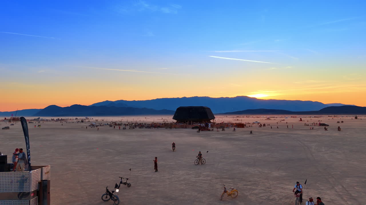 Nevada, USA, 15 August 2025: Blue hour landscape of desert festival with art car. Wide view of a mobile music stage and bicycles in the playa under a deep blue evening sky
