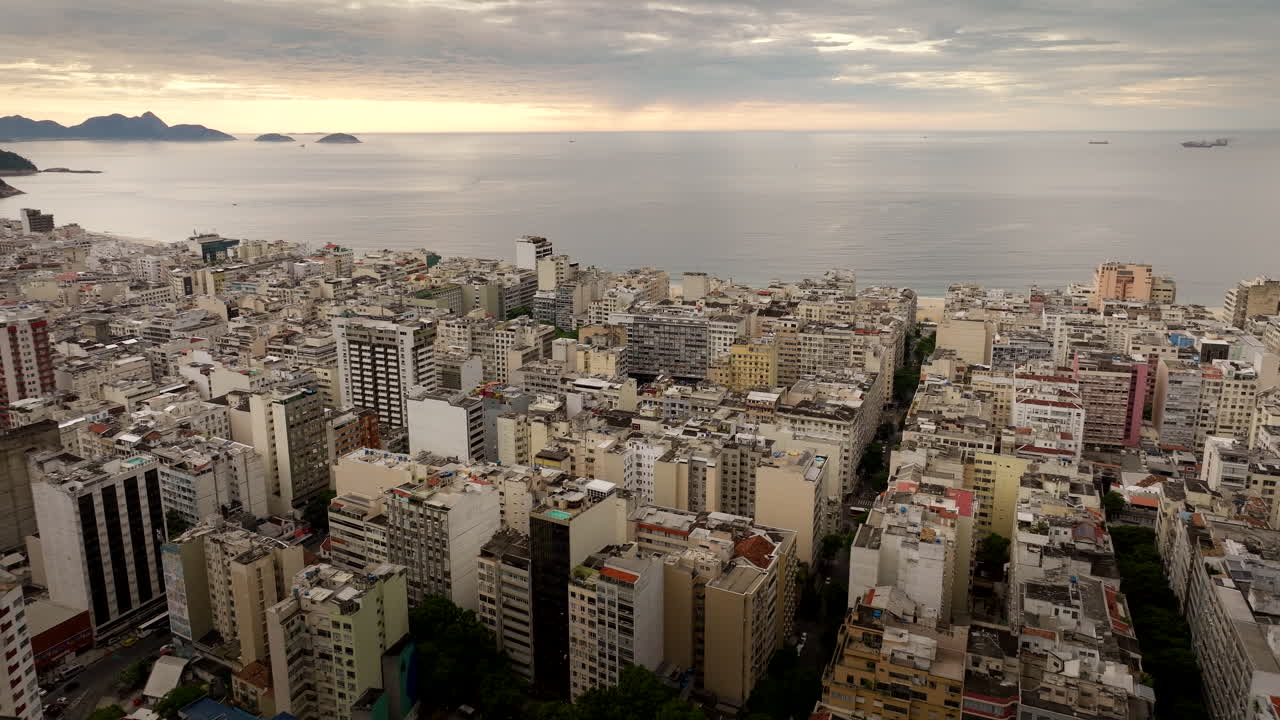 Sunrise aerial flight over Copacabana neighborhood rooftops toward beach, Rio