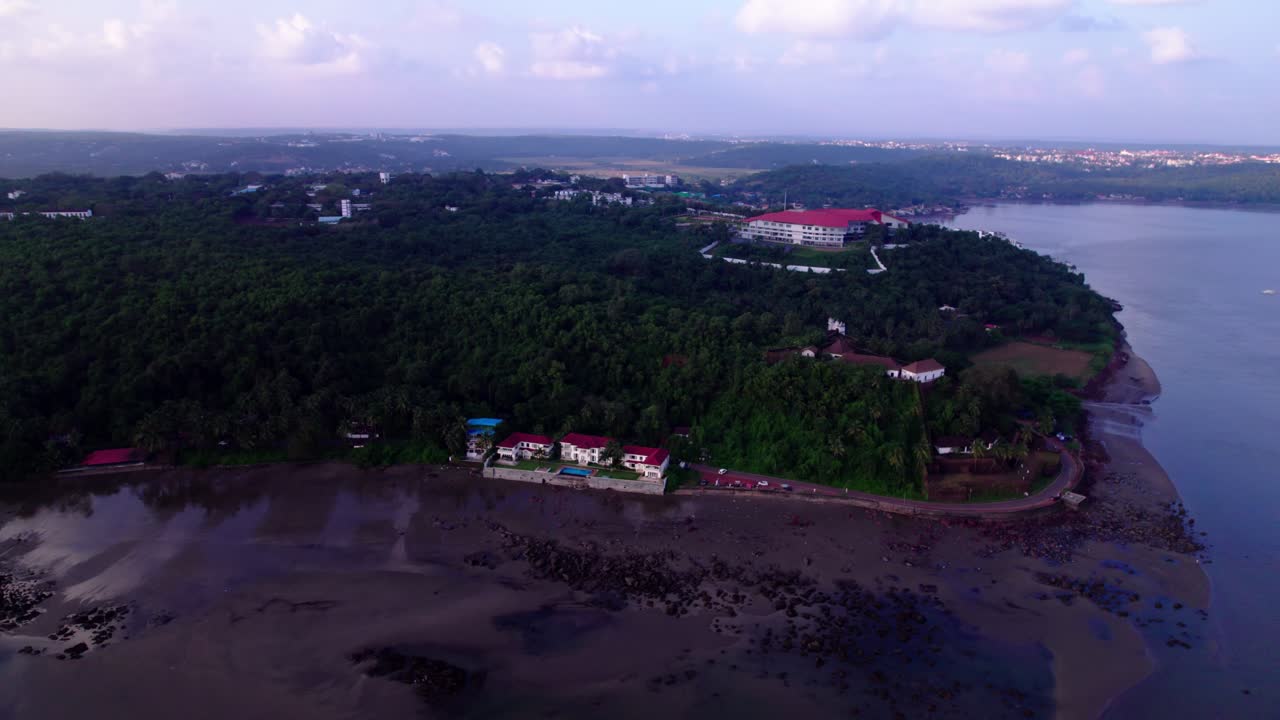 Aerial view of Quegdevelim Beach with Urban forest, Naval War College and Reis Magos Fort at Panaji, goa, india. day time, circle shot, drone shot, 4k