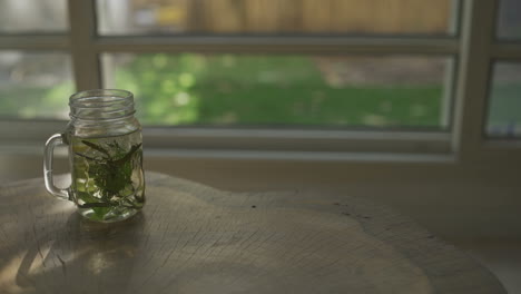 herbal tea glass is set down on table overlooking garden