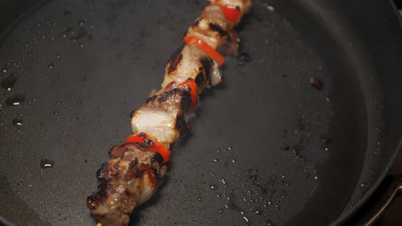 Spiedino di carne e verdure cotto in una padella nera nell'olio di arachidi.