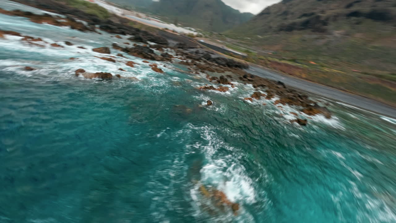 FPV drone glides over La Palma's rocky coastline, serene ocean view