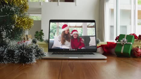 Lächelnde-Kaukasische-Mutter-Und-Tochter-Mit-Weihnachtsmützen-Bei-Einem-Weihnachtsvideoanruf-Auf-Dem-Laptop