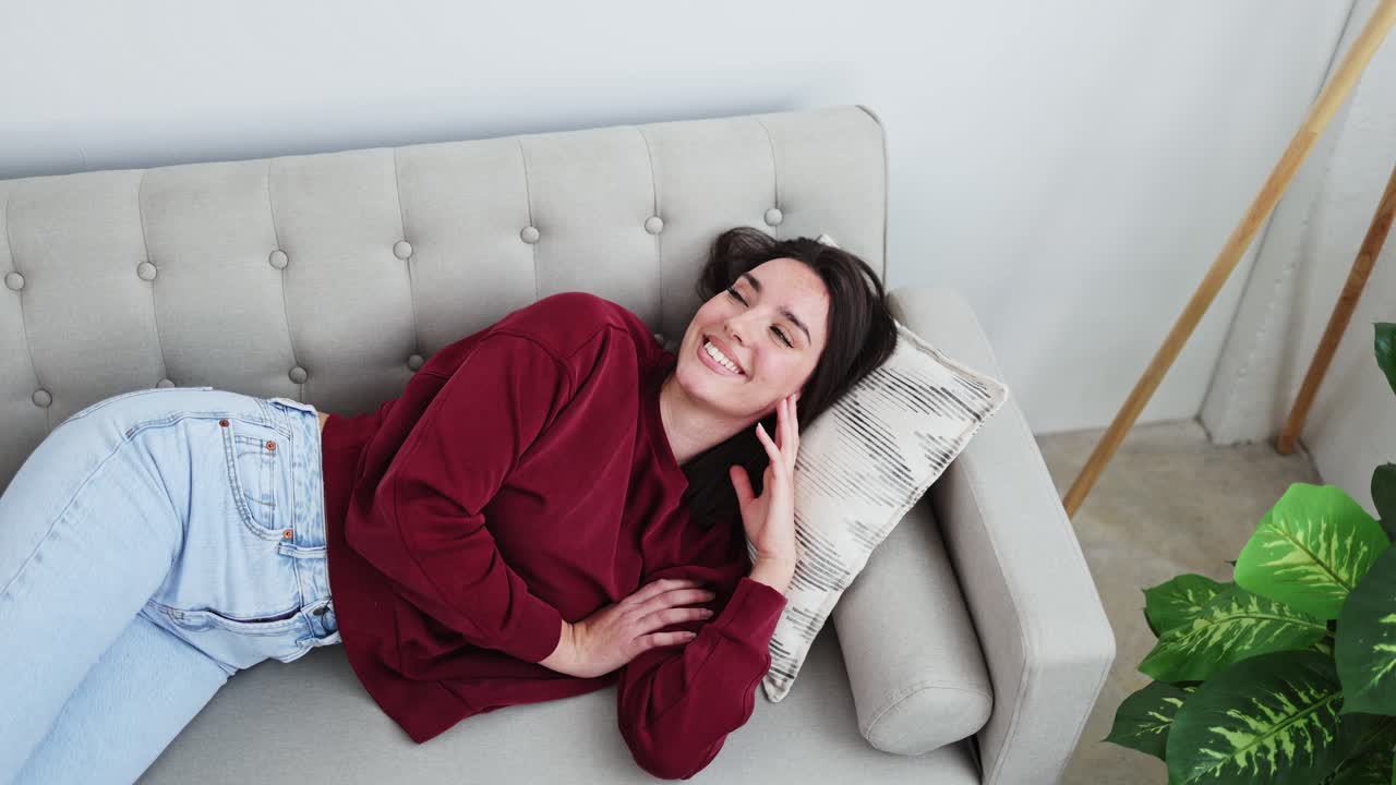 Giovane donna che si rilassa e sorride su un comodo divano