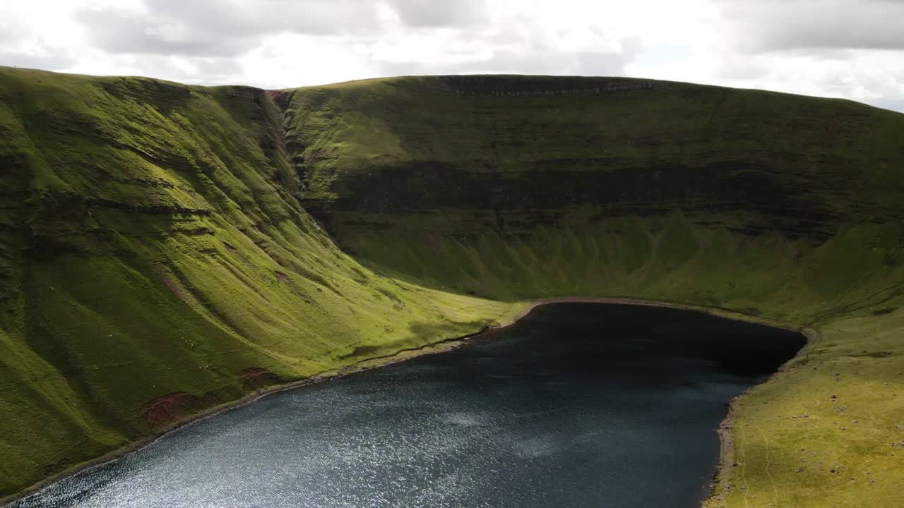 hiperlapso aéreo del lago natural rodeado de montañas cubiertas de verde en el parque nacional de brecon beacons, gales