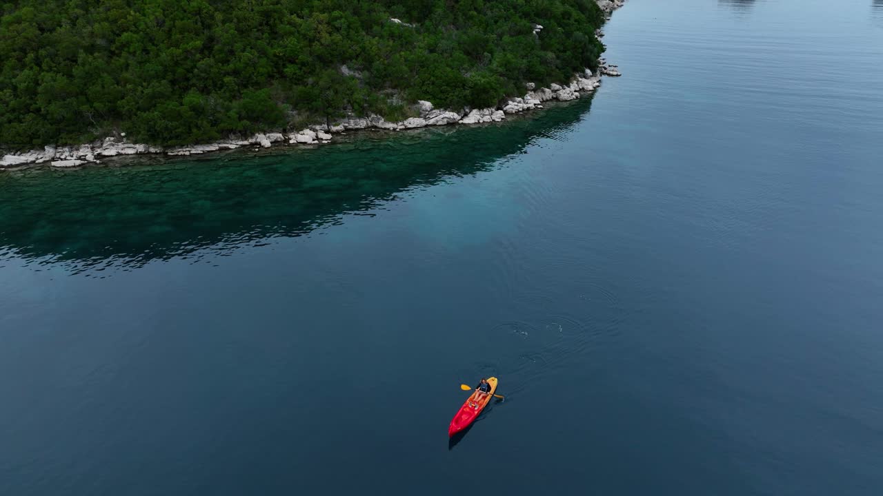 Aerial view of a persona canoeing alone on a beautiful river.
