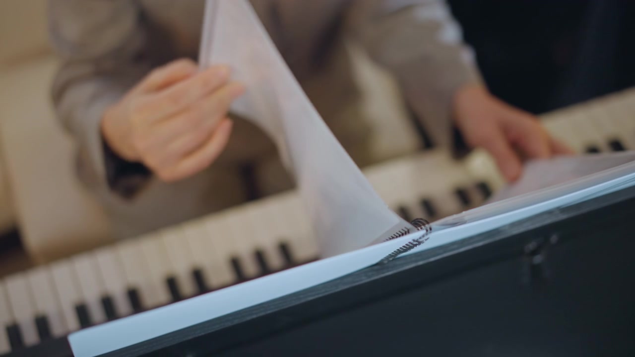 Insegnante che organizza attentamente gli spartiti. Istruttore concentrato che sistema con fermezza gli spartiti. Musicisti che si esercitano meticolosamente mentre l'istruttore sfoglia le pagine e segna le notazioni musicali durante le prove.
