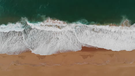 vista aérea horizontal de arriba hacia abajo de la hermosa playa de arena, océano de agua verde y olas rompiendo en la orilla del mar, paisaje marino relajante