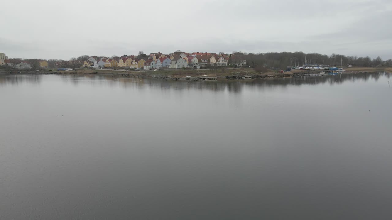 volando un dron sobre el agua tranquila y tranquila en karlskrona, suecia, con vistas a las hermosas casas suecas en salto en el fondo