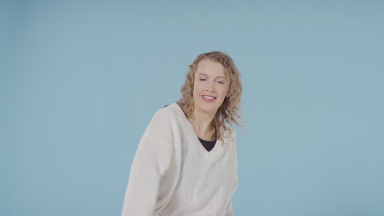 студийный снимок молодой женщины, весело танцующей на голубом фоне 5