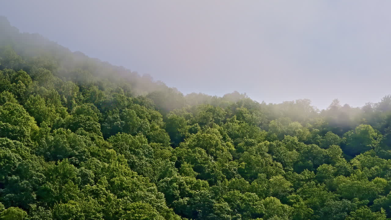 Cinematic aerial shot approaching hazy mountain peaks