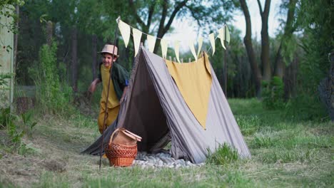 active children, cheerful boys are happy to run around wigwam, relaxing in fresh air among trees on summer weekend