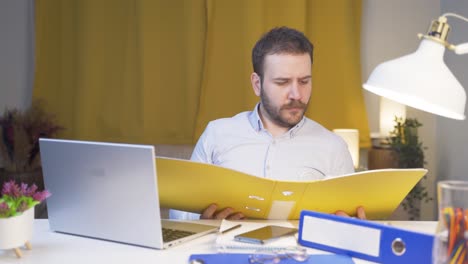 trabajador de oficina en casa revisando archivos de papeleo.