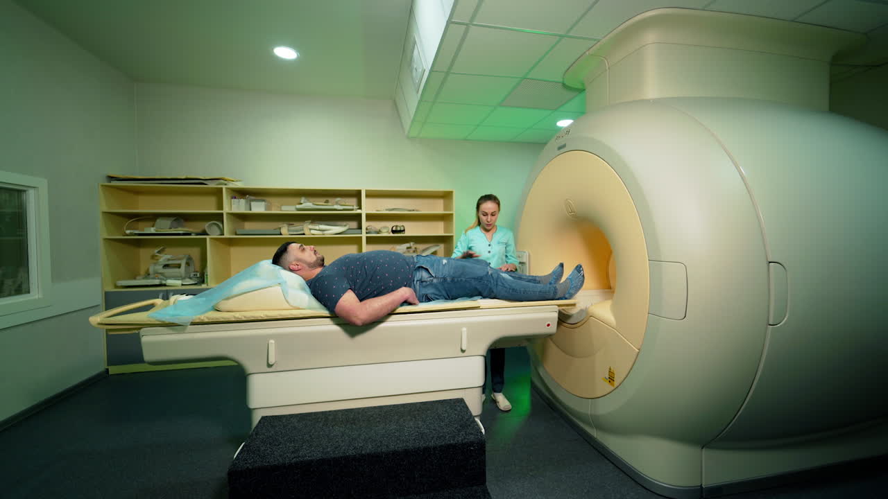 Advanced medical technologies in hospital. Man patient lying in magnetic resonance image device. Female technician helps the patient near MRI device.