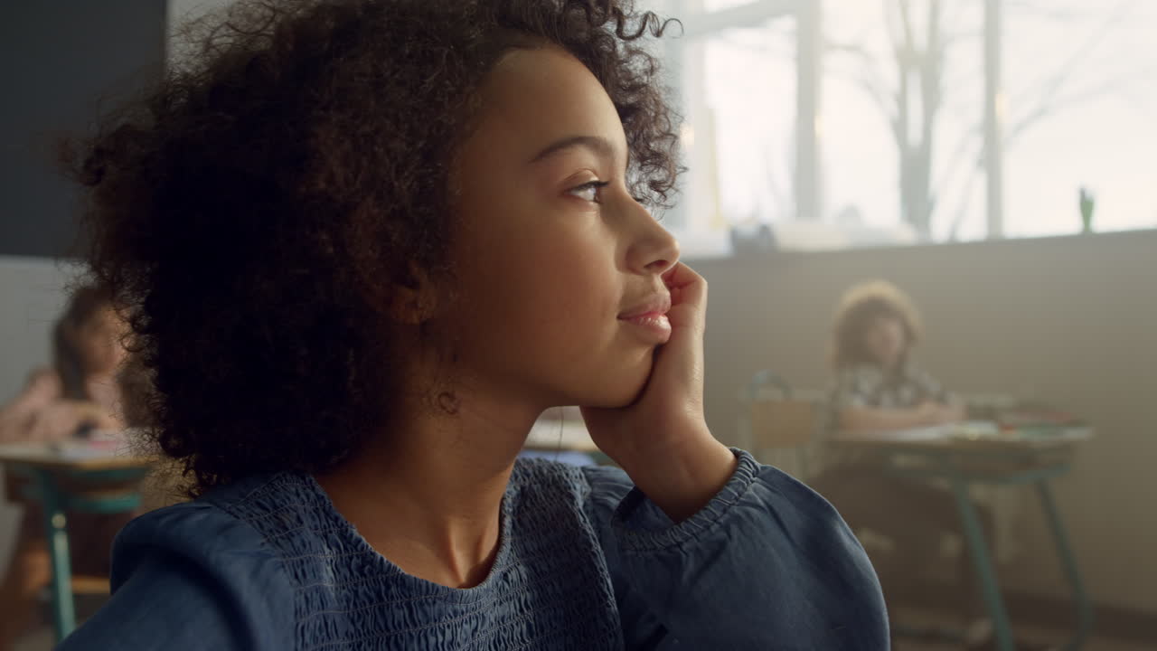 Thoughtful pupil sitting in classroom. African girl boring during lesson