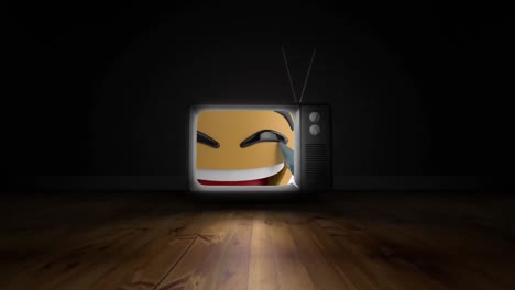 digital animation of laughing face emoji on television screen on wooden surface on black background