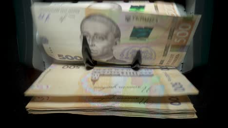 ukrainian hryvnia banknotes being processed by a counting machine