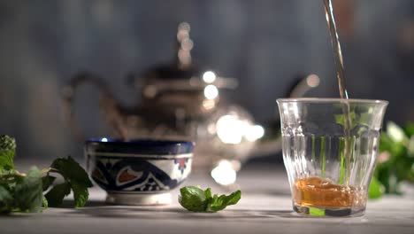 cinemagraph of tea starting pouring into a glass with moroccan tea set and mint