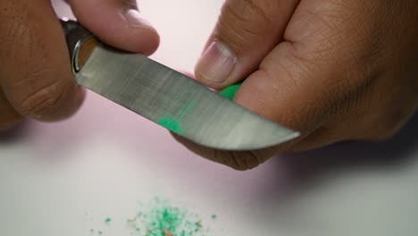 imágenes de manos afilando lentamente un lápiz y algunos lápices de colores con un cuchillo afilado