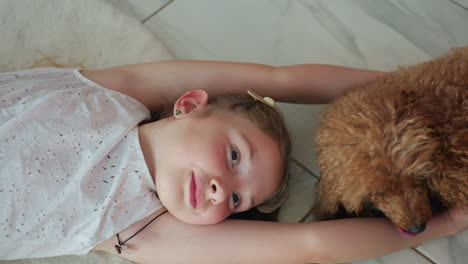 pretty young girl in white gown lying on white rug, smiling as her dog licks her hand. enjoying playful and tender moments with pet, creating joyful bond