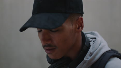 retrato de cerca joven de raza mixta feliz hombre escuchando música se quita los auriculares mirando a la cámara hombre étnico confiado que usa moda hip hop de moda