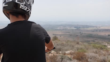 rear close-up view of a mountain biker admiring the beautiful scenery on top of a mountain