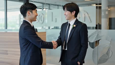 business professionals shake hands in modern office setting during daytime