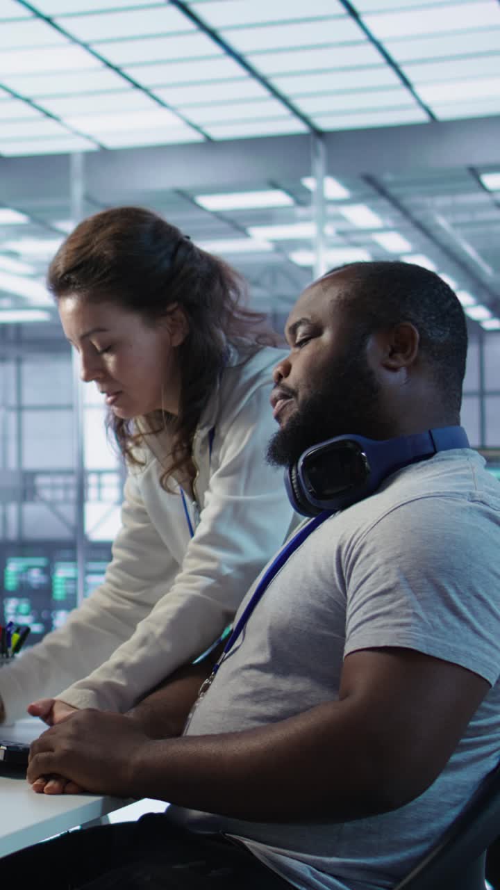 Vertical video Team leader teaching IT specialist how to while monitor AI supercomputers