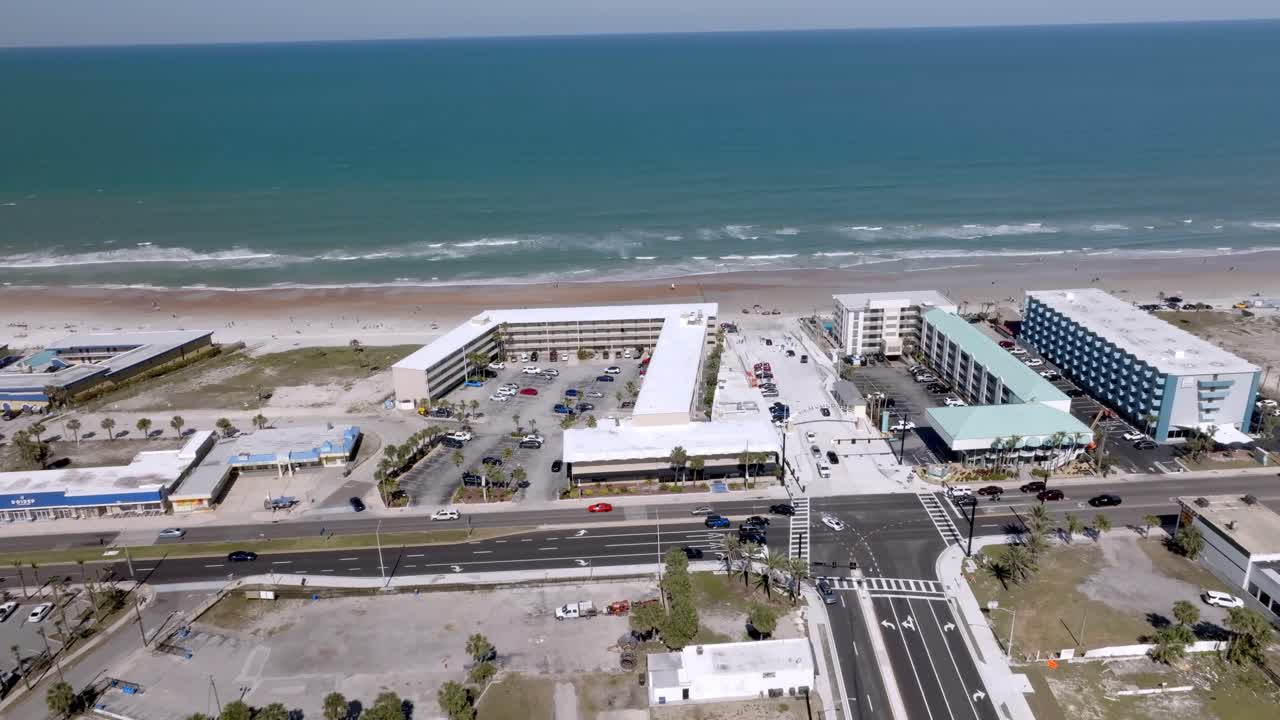 Daytona Beach, Florida with waves from the Atlantic Ocean, vehicles, hotels and people on the beach with drone video stable.