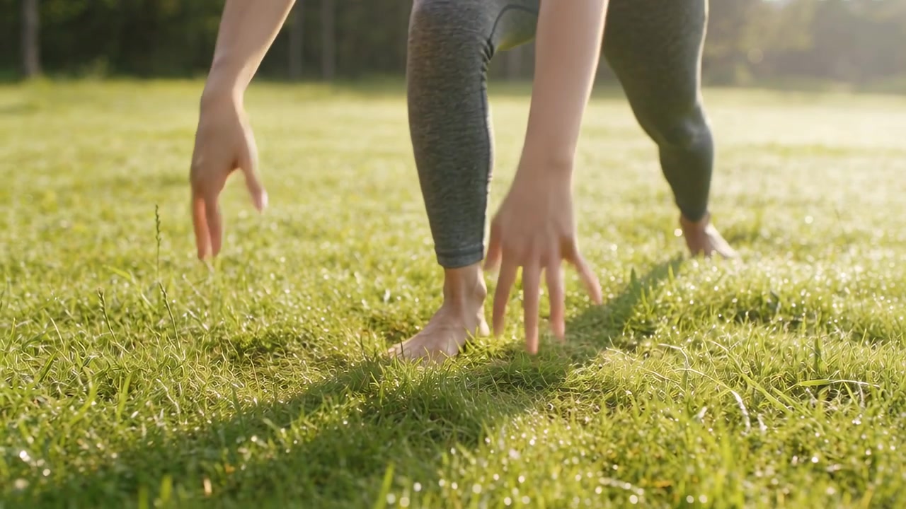 Starting hand balance woman in leggings practicing low lunge flow on sunlit grass, hands pressing