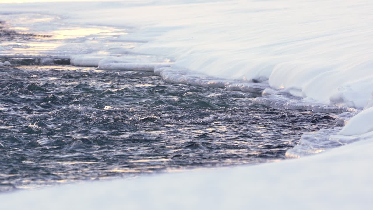 Pristine river with rapid water flow in froze snow covered polar scenery. River in Patagonia during winter, Argentina, near El Chalten