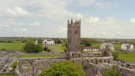 claregalway friary at center of overcast sky as drone orbit and ascends