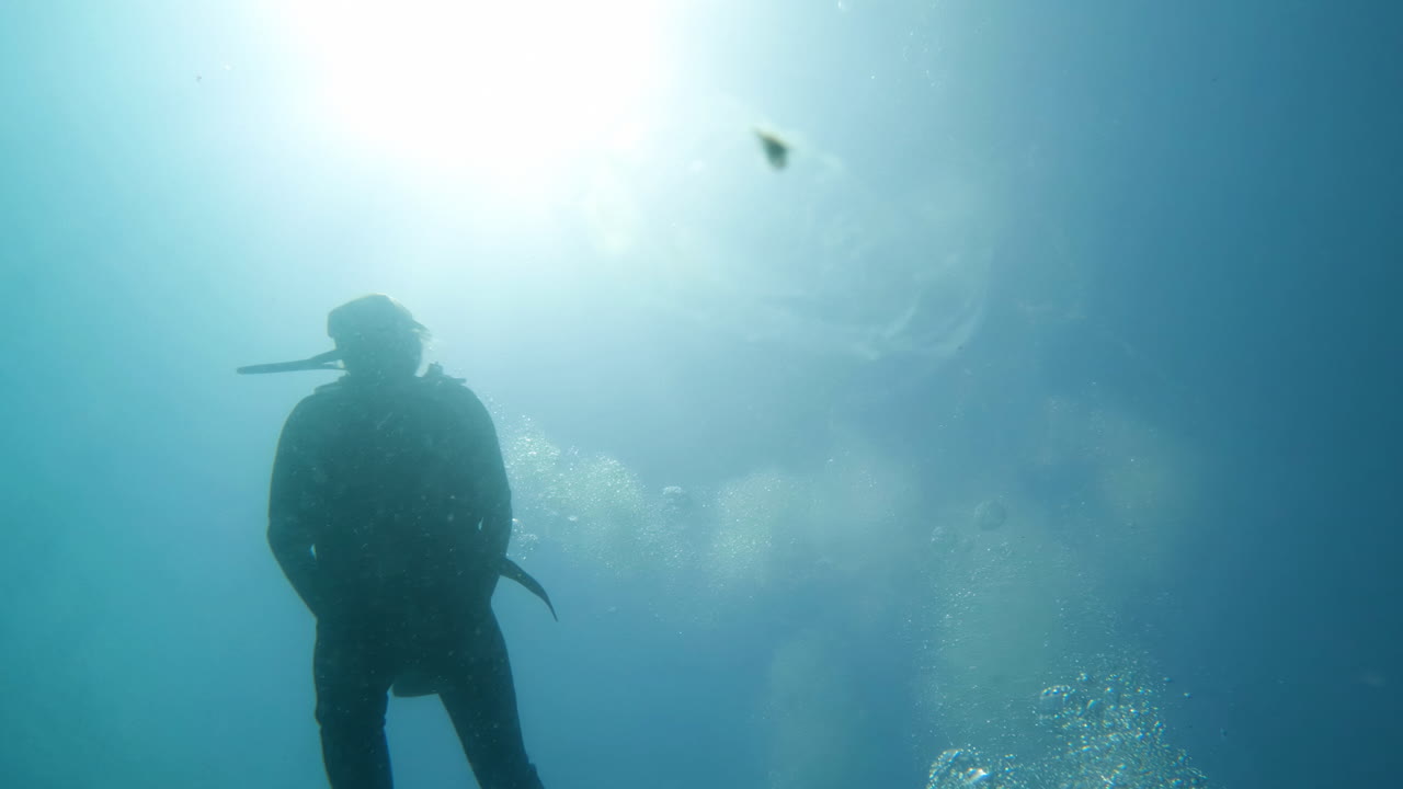toma cinematográfica en cámara lenta de un buzo submarino en aguas azules claras con burbujas de aire en 4k, 120 fps, slomo