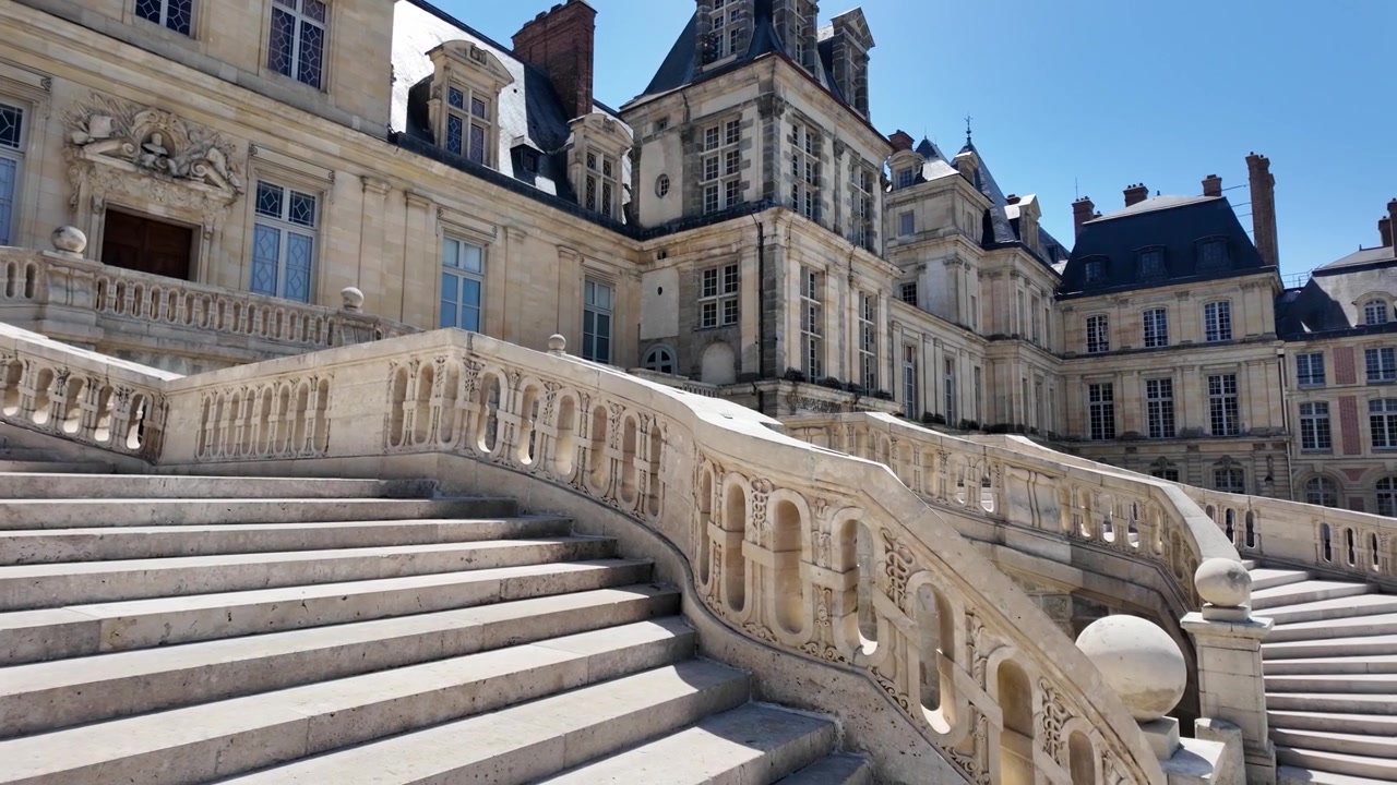 Powolne panoramowanie w prawo po Schodach Podkowy i fasadzie pałacu w Château de Fontainebleau, prezentujące historyczną francuską architekturę renesansową we Francji